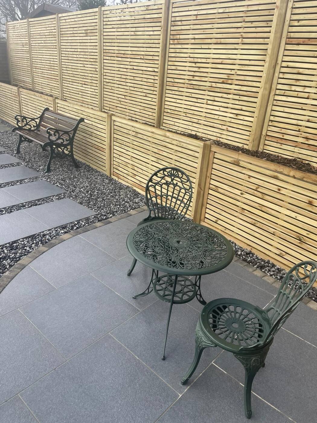 Slatted timber fencing behind a grey porcelain patio with bistro set